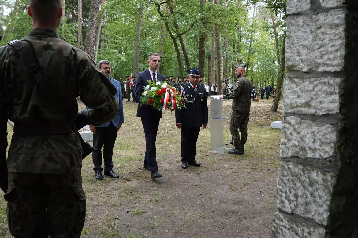 Delegacja samorządowa składa wiązankę pod tablicą pamiątkową