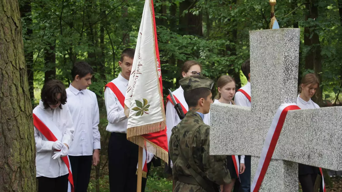 Uczestnicy podczas uroczystości. Uczniowie i harcerze obok jednego z kamiennych krzyży